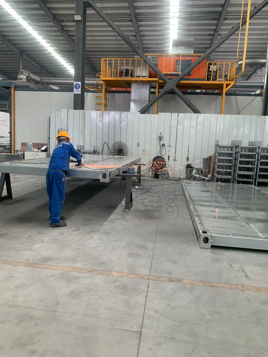 A worker grinding a steel building frame in the workshop